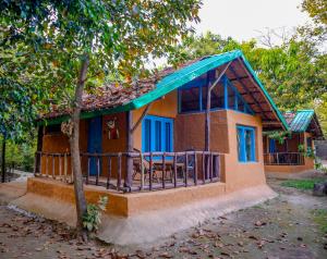 a small house with a porch with a blue roof at Camp Hornbill Corbett in Rāmnagar