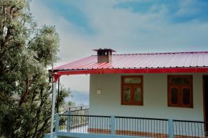 a house with a red roof and a balcony at Jigyasa Homestay in Almora