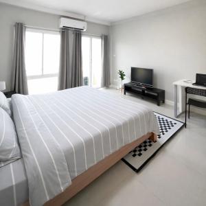 a white bedroom with a large bed and a desk at Mayeen cat hotel in Chiang Mai +1 photo