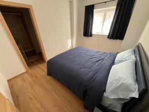 a bedroom with a bed with a blue comforter and a window at Casa Vian in Vigo di Fassa