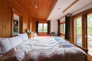 a large bed in a room with wooden walls and windows at Le Bois-Gentil in Gryon
