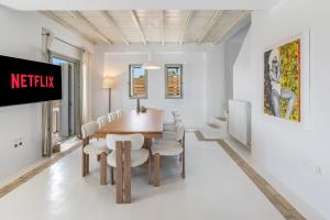 a dining room with a table and chairs and a tv at Your private Mykonos Villa in Kalafatis
