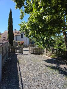 a fence in front of a house with a tree at La mare aux canards in Châteauvieux