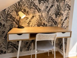 a desk with a lamp and a chair at Appartement calme et spacieux, tout équipé in Saint-Quentin