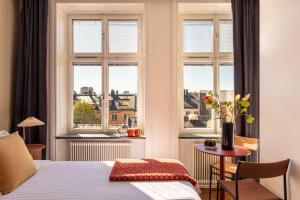 a bedroom with a bed and a table and windows at Bob W Stockholm Södermalm in Stockholm +29 photos