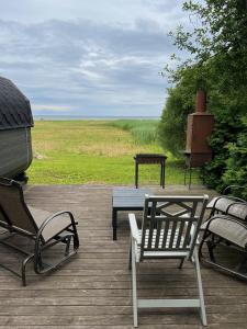 a patio with two chairs and a table and a grill at Mazā Kaija in Bērzciems