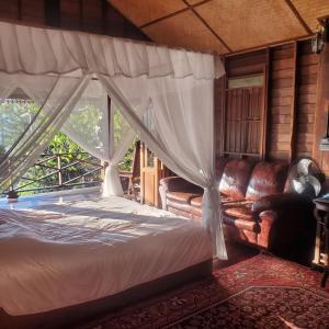 a bedroom with a canopy bed and a couch at Camelliana Horizon Pongyang - Nature Retreat in Mae Rim +152 photos