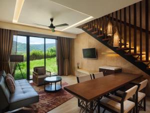 a living room with a dining table and a staircase at dusitD2 Khao Yai in Mu Si