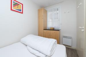 a small bedroom with a white bed and a window at Appartement 4p - piscine partagée in Arzon