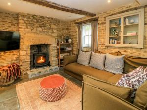 a living room with a couch and a fireplace at Well Cottage in Chipping Norton