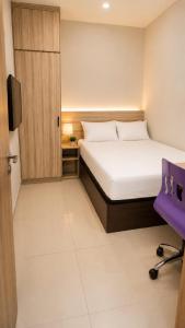 a small bedroom with a bed and a chair at Merryland ICE BSD City in Tjilandak +6 photos