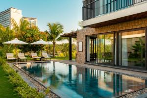 an infinity pool with chairs and umbrellas next to a building at Amiana Resort Cam Ranh in Cam Ranh