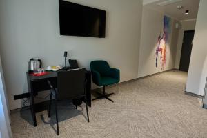 a room with a desk and a green chair at Hotel Nowa Bukowa in Katowice