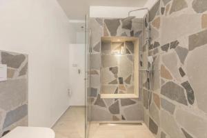 a bathroom with a shower with a stone wall at Uhse Ferienwohnung Delux mit Loft in Heide +20 photos