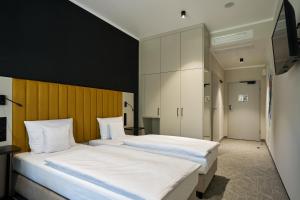 two beds in a room with white sheets at Hotel Nowa Bukowa in Katowice