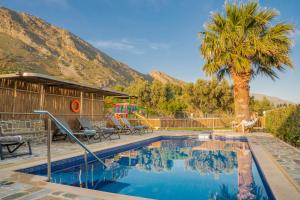 a swimming pool with a palm tree and a house at Dafni Villa a place to visit by Rentado in Orné