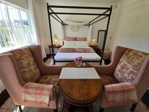 a hotel room with a bed and a table and chairs at Amourette's Rose Cottage in Centurion