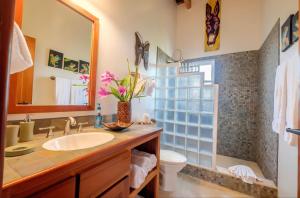 a bathroom with a sink and a toilet and a mirror at Indigo Belize Beach 2C in San Pedro