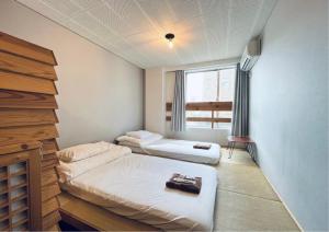 a small room with two beds and a window at Yado 1889 in Fujiyoshida