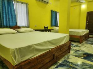 a bedroom with two beds and a yellow wall at Hotel Navin Palace Pirpainti in Bhāgalpur +16 photos