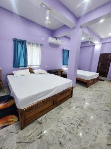 two beds in a room with purple walls at Hotel Navin Palace Pirpainti in Bhāgalpur