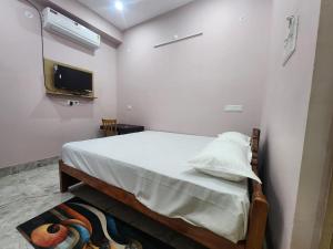 a bedroom with a bed with white sheets and a tv at Hotel Navin Palace Pirpainti in Bhāgalpur