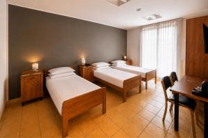 ein Zimmer mit drei Betten, einem Tisch und einem Schreibtisch in der Unterkunft Phi Hotel Homy Druento in Druento + 38 Fotos