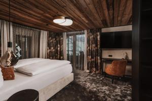 a hotel room with a bed and a television at NANI - Mountain Chalet in Saalbach-Hinterglemm +78 photos