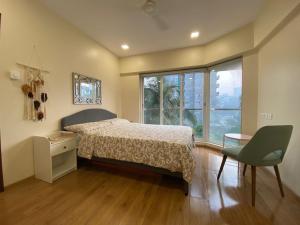 a bedroom with a bed and a table and a window at ConnektHomes - Modern2Bed-BandraArea in Mumbai