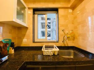 a kitchen counter with a sink and a window at ConnektHomes - Modern2Bed-BandraArea in Mumbai