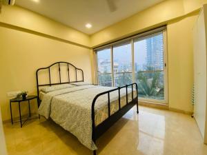 a bedroom with a bed and a large window at ConnektHomes - Modern2Bed-BandraArea in Mumbai