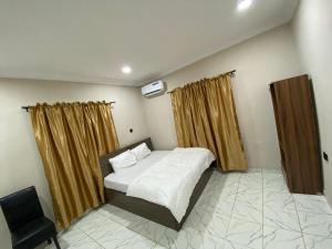 a bedroom with a bed and curtains and a chair at MerryJay Hotels in Otta