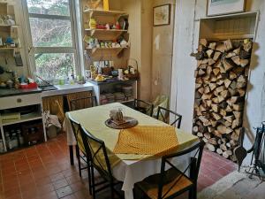 a table and chairs in a kitchen with a pile of wood at Cottage LAISSER VERDURE in Gargilesse-Dampierre