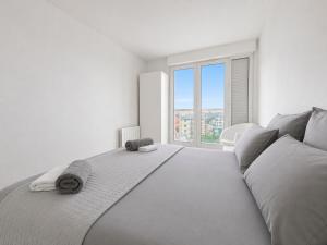 a white bedroom with a bed and a large window at Porte de Paris, spacieux T3, terrasse et parking in Vanves