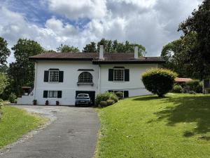 a white house with a car parked in the driveway at Gure gostuan in Itxassou