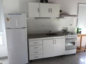 eine Küche mit weißen Schränken und einem weißen Kühlschrank in der Unterkunft Soñada in Tandil