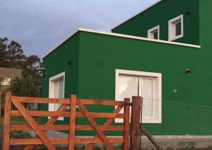 une maison verte avec une clôture en bois devant elle dans l'établissement Soñada, à Tandil