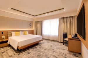 a hotel room with a bed and a flat screen tv at Regenta Place CG Road in Ahmedabad