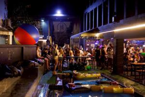 a crowd of people standing around a bar at night at BED STATION Hostel Khaosan in Bangkok +72 photos