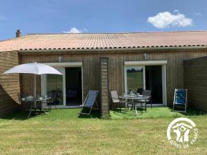 a house with a table and chairs and an umbrella at Au brunet in Saint-Élix-Theux