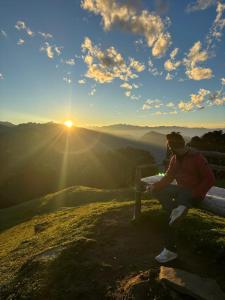 a person sitting on a bench on top of a mountain at Raghupur trecking camp in Shoja +23 photos
