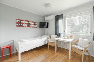 a white bedroom with a bed and a table and chairs at FolkiaCenter Gästhem - Vieraskoti - Guesthouse in Hanko