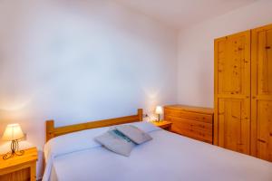 a bedroom with a white bed and wooden cabinets at Paradiso in Costa Paradiso