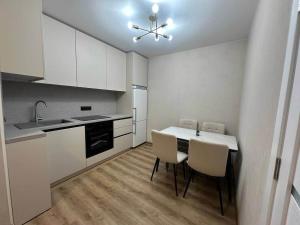 a kitchen with white cabinets and a table and chairs at Central cozy apartments- one and two bedrooms option in Chişinău