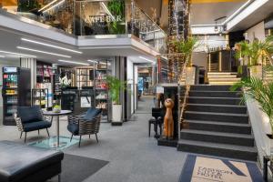 a lobby of a store with stairs and plants at Fashion City Hotel Superior in Budapest