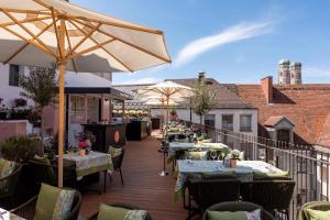 eine Terrasse mit Tischen und Sonnenschirmen auf einem Balkon in der Unterkunft Louis Hotel in München