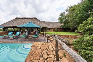 a resort with a swimming pool and a thatch roof at Sable Ranch Thaba Khaya Lodge in Brits