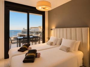 two beds in a bedroom with a view of the ocean at Infinity View Penthouses by NRAS in Arenales del Sol