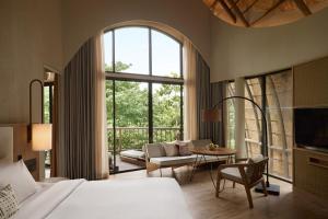 a bedroom with a bed and a couch and a table at dusitD2 Khao Yai in Mu Si +74 photos