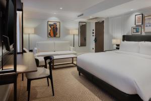 a bedroom with a white bed and a living room at Radisson Blu Hotel, London Bloomsbury in London